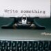 Vintage typewriter with a sheet of paper that reads “Write something.”