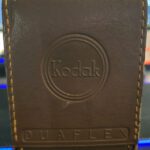 A Story Hidden in the Case Vintage Kodak Duaflex camera case standing upright on a wooden table.