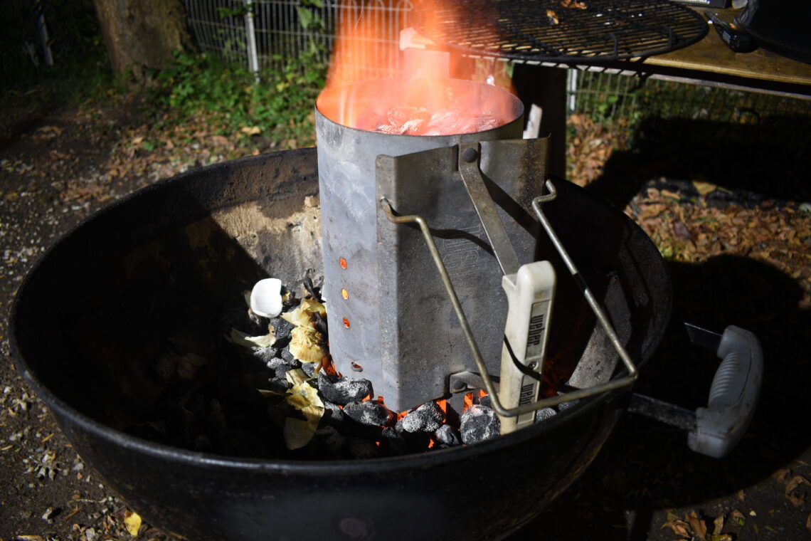 Charcoal grill with a chimney starter lit at night during a late-night cookout
